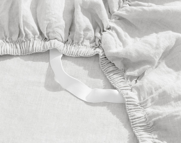 Close-up on a loose Signature European Linen Fitted Sheet in White to show its Stay Snug elastic band and soft linen fabric.