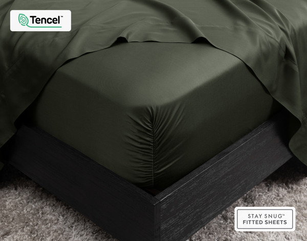 Gros plan sur le coin de notre BeechBliss Fitted drap en Rainforest Green, qui s'adapte parfaitement à un matelas sur lequel est posé un drap plat drap .