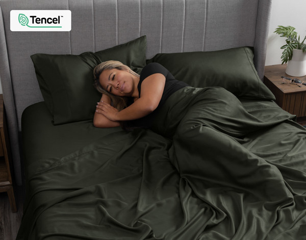 Femme emmitouflée dans notre BeechBliss TENCEL™ Modal drap ensemble  en Rainforest Green faisant la sieste sur le côté.