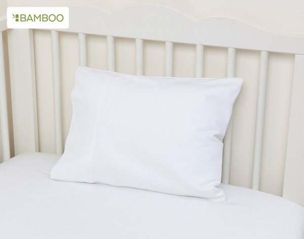 Our Bamboo Cotton Crib-Sized Pillowcase in White leaning against the back of a cream white crib.