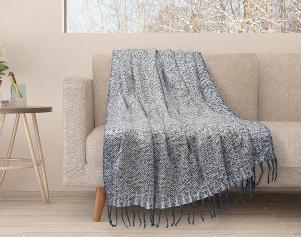 Our Grey Mix Herringbone Knit Fringe Throw draped over a couch.
