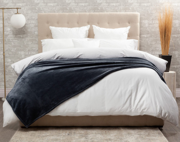 Our Blue-Grey Cashmere Touch Fleece Blanket in Sea Storm dressed over a comfortable white bed.