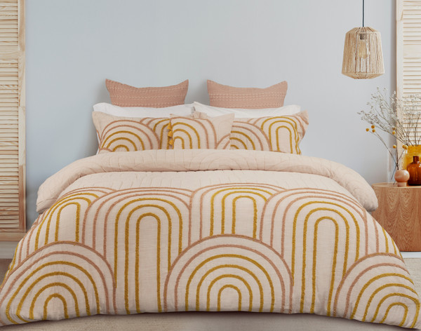 Notre housse de couette Maeve présente un élégant touffetage circulaire orange sur une surface en chenille crème rose blush .