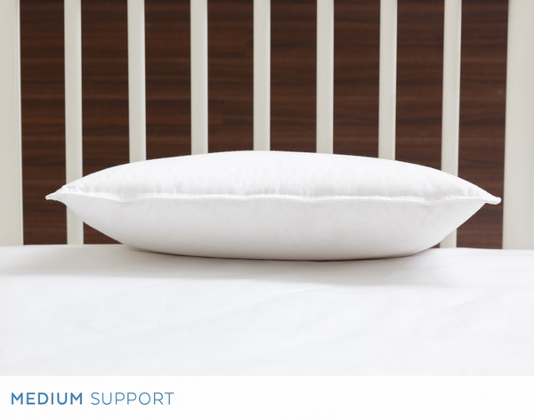 Front view of our Petite Down Pillow resting flat in front of a crib headboard.