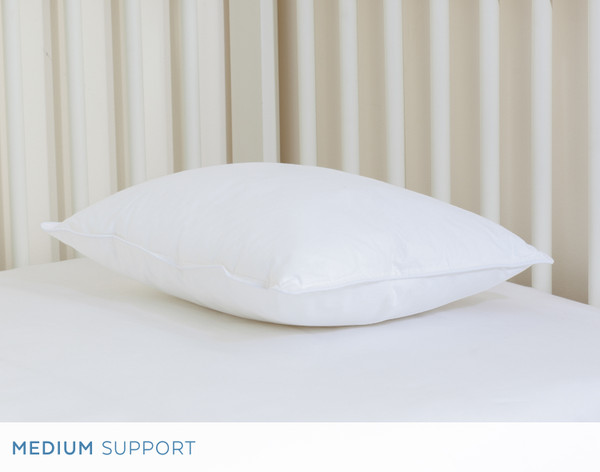 Angled view of our Petite Microfiber Pillow resting flat in front of a crib headboard.