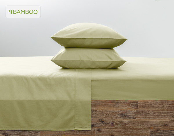 Deux de nos taies d'oreiller Bamboo Cotton en vert orme empilées l'une sur l'autre sur un lit rose coordonné.