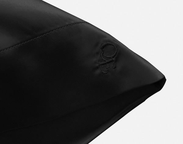 Corner of our Mulberry Silk Pillowcase in Black Pearl to show its embroidered QE Home logo.