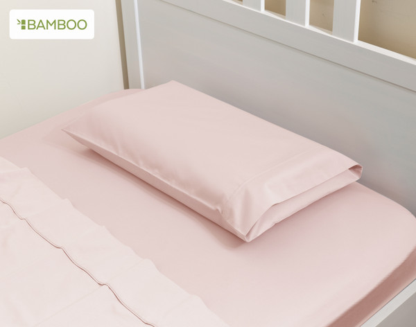 Angled view of our Small Bamboo Cotton Pillowcase in Blush Pink in a children's white bed.
