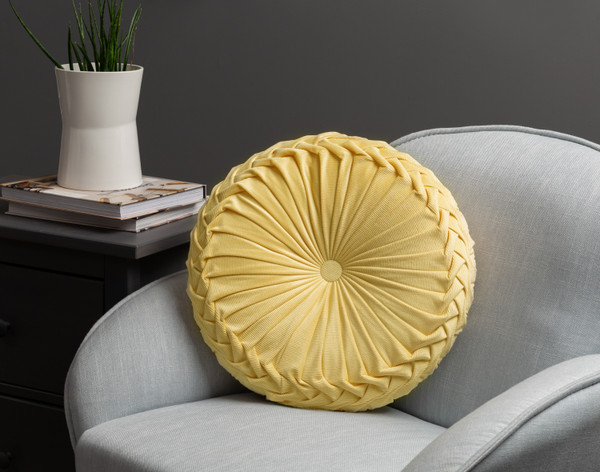 Front view of our Pin-Tuck Round Corduroy Cushion in _______ sitting against the back of a small grey armchair.