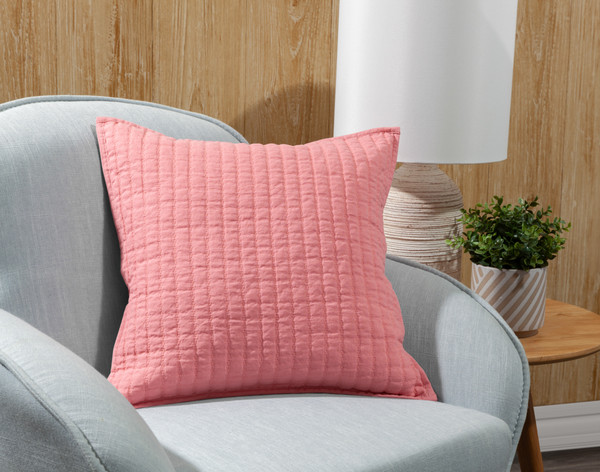 Notre housse de coussin carrée en lin et coton Fuchsia s'appuie sur un fauteuil gris.