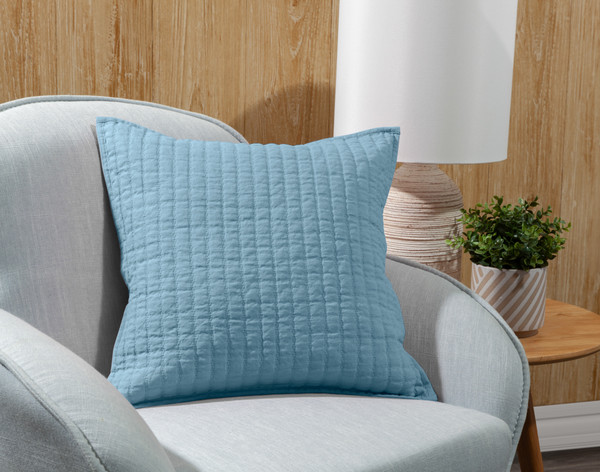 Our Linen Cotton Square Cushion Cover in Lake leaning in a grey armchair.