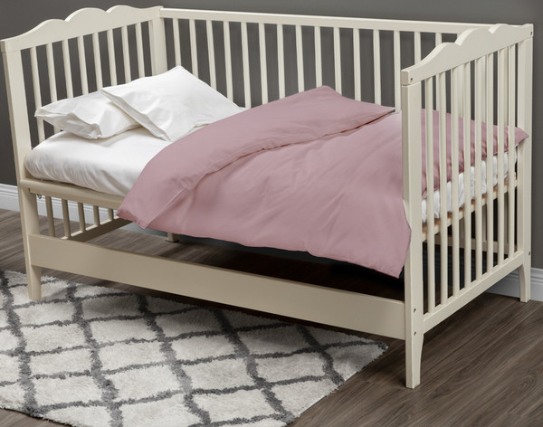 Our Bamboo Cotton Crib-Sized Duvet Cover in Orchid Pink dressed over a small white mattress in a cream white crib.
