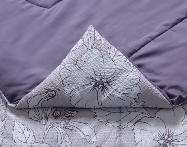 Folded corner on our Tessa Recycled Polyester Comforter Set to show its patterned surface and solid reverse side-by-side.