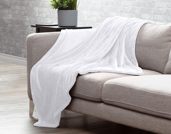 Our Velvet Plush Throw in Magnolia draped over a beige couch in a white living room.