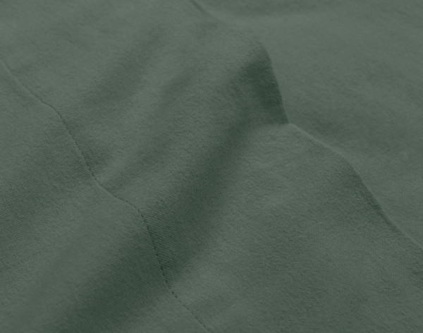 Close-up on the edge of the flat sheet for our Organic Flannel Cotton Sheet Set in Pine Green to show soft cotton flexibility.