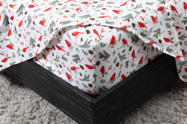 Angled view of our Organic Flannel Cotton Sheet Set in Holly Jolly wrapped snug around a mattress corner with its flat sheet hanging over.