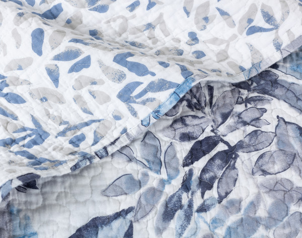 Close-up on a folded edge of our Sawara Cotton Quilt Set to show its large face and small reverse botanical patterns.