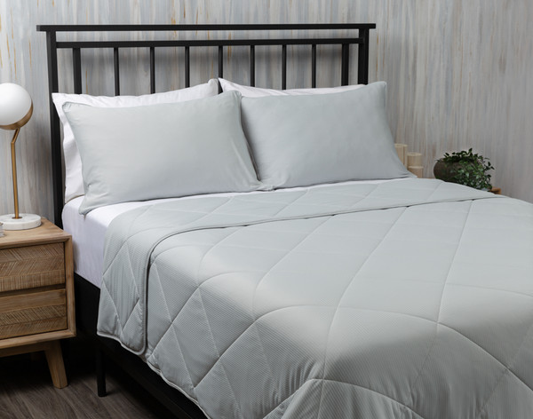 Vue en angle de notre couverture Cool Touch à rayures grises étalée sur un grand lit.