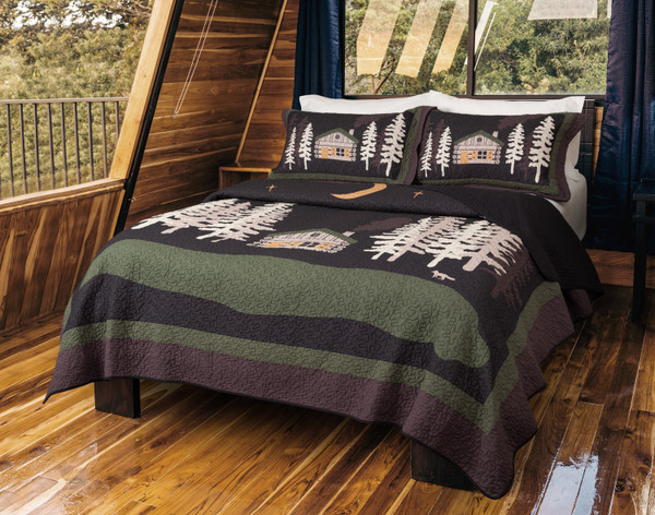 Angled view of our Rock River Cotton Quilt Set in a windowed cabin bedroom with wooden floors and forest views.