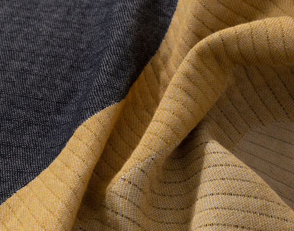 Close-up on the light ribbed texture on the soft gold and black segments of our Estrela Throw.