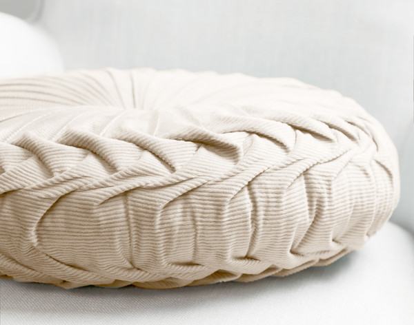 Side view of our Pin-Tuck Round Corduroy Cushion in Sandstone White to show its detailed pleated edge.