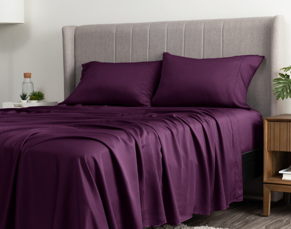 Angled view of our BeechBliss TENCEL™ Modal Sheet Set in Plum draped casually over a queen bed with no duvet cover or coordinating accessories.