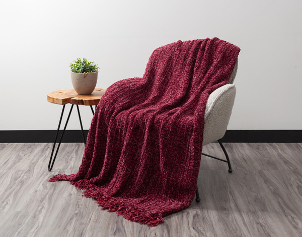 Angled view of our Chunky Chenille Throw in Shiraz sitting in a grey armchair.