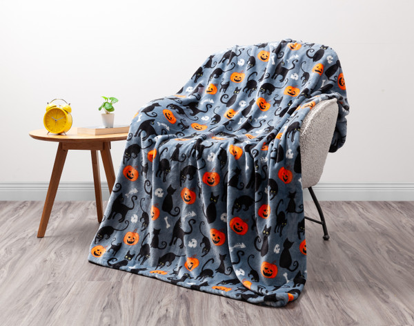 Front view of our Black Cat Halloween Fleece Throw draped over a white chair in a minimalist living room.