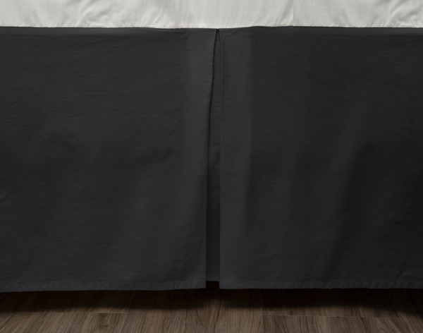 Close-up of our Cotton Twill Bedskirt in Black Pearl draped along the side of a bed frame.