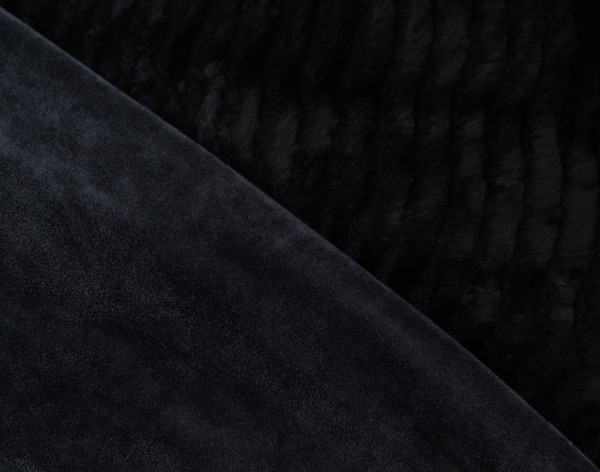 Close-up on the folded edge of our Tiered Plush Throw in Black to show its waving surface and smooth reverse together.