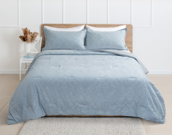 Front view of our Cortina Cotton Matelassé Comforter Set in Blue dressed over a queen bed in a clean white bedroom.