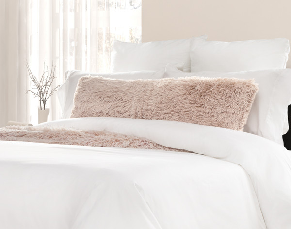 Vue de face de notre oreiller lombaire Camellia givré posé sur un lit blanc avec une couverture coordonnée.
