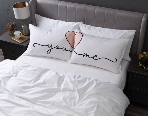 Aerial view of our You Heart Me Pillow Talk Pillowcases dressed over queen pillows in a large white bed.