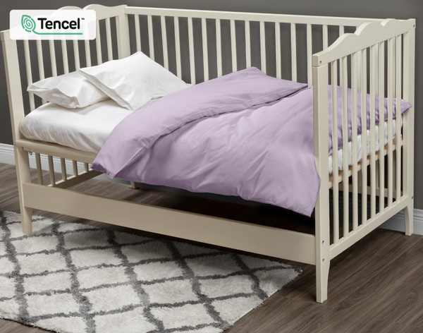 Notre housse de couette Eucalyptus Luxe pour lit d'enfant Shoreline habille un petit matelas blanc dans un lit d'enfant blanc crème. 