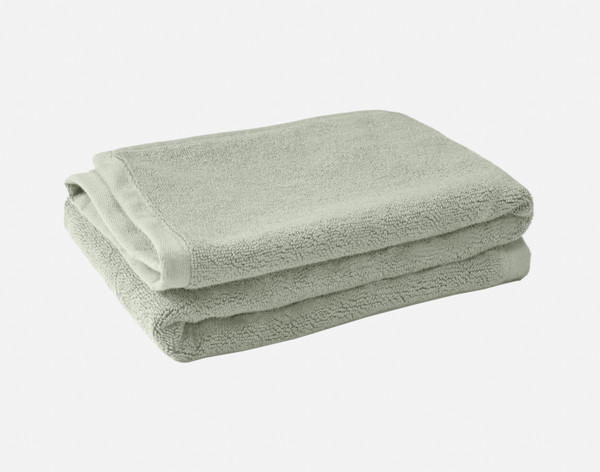 Pile pliée de nos tapis de bain en coton modal de couleur jadéite sur un fond blanc uni.