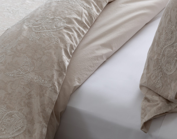 Close-up on our Prescott Duvet Cover folded over a white sheeted bed to show its tonal beige colour clearly.