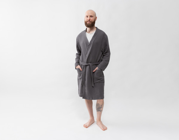 Front view of a man wearing our Muslin Gauze Bathrobe in Charcoal standing in a solid white room.