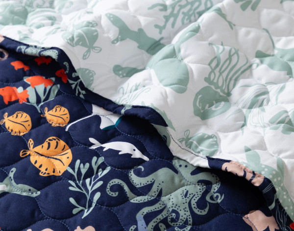Folded edge on our Sea Creatures Coverlet Set to show its surface and backing patterns together.
