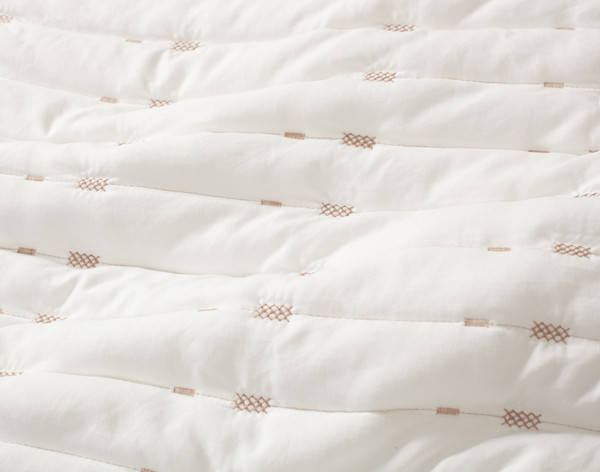 Close-up on the stitched lines and extra soft, lightweight recycled microfiber surface on our Madison Coverlet Set.