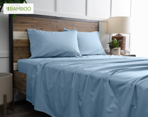 Side view of our Bamboo Cotton Sheet Set in Mistral Blue dressed over a wooden bed in a white bedroom.