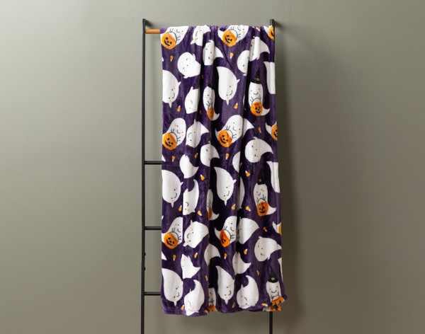 Front view of our Casper Halloween Fleece Throw hanging on a tall rack against a  solid grey wall.