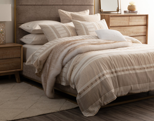 Angled view of our Adrift Duvet Cover dressed with accessories over a queen bed in a modern room.