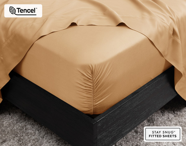 Close-up of the corner on our BeechBliss TENCEL™ Modal Fitted Sheet in Gilded snugly fit over a mattress with a flat sheet draped on top.