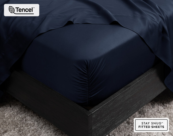 Close-up of the corner on our BeechBliss TENCEL™ Modal Fitted Sheet in Deep Space snugly fit over a mattress with a flat sheet draped on top.