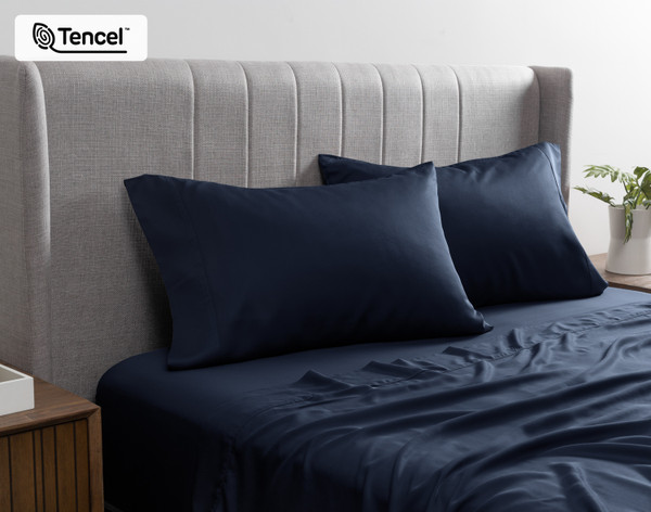 Front view of our BeechBliss TENCEL™ Modal Pillowcase in Deep Space resting against a headboard in a bed with matching sheets.