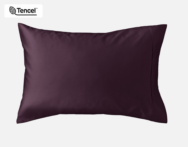 Angled view of our Eucalyptus Luxe TENCEL™ Lyocell Pillowcases in Purple sitting against a headboard of a beige queen bed.