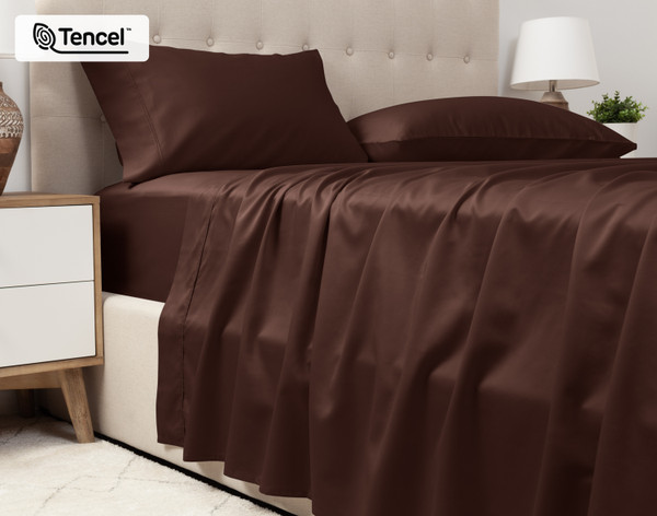 Lower view of our Eucalyptus Luxe TENCEL™ Lyocell Sheet Set in Chestnut to show its flat sheet draped over the side of a queen bed.
