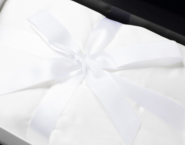 Our Silk Blend Fitted Sheet in Snow wrapped in a square with a white bow.