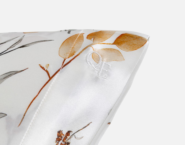 Close-up on the embroidered QE Home logo on the corner of our Willow Mulberry Silk Pillowcase.