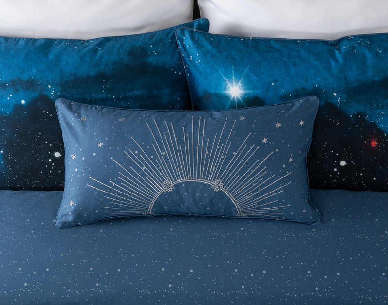 Front view of our Supernova Boudoir Pillow Cover leaning against coordinating pillows.